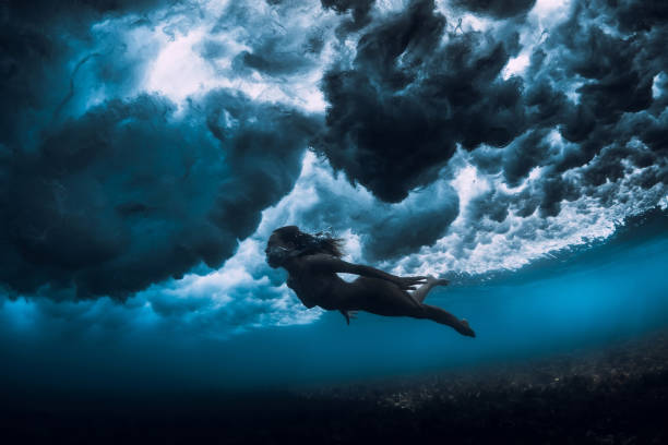 istock Woman in bikini dive without surfboard underwater with ocean wave. Duck dive under barrel wave 1171252986