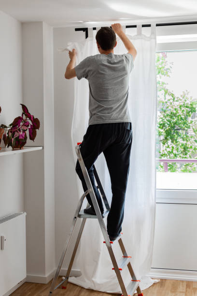 istock Man hangs white curtains on the curtain rod 1171253736