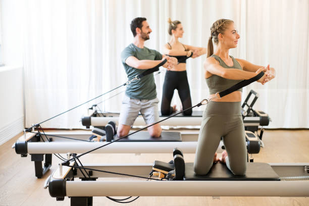 tre persone che esercitano la rotazione del toro in palestra - pilates machine foto e immagini stock