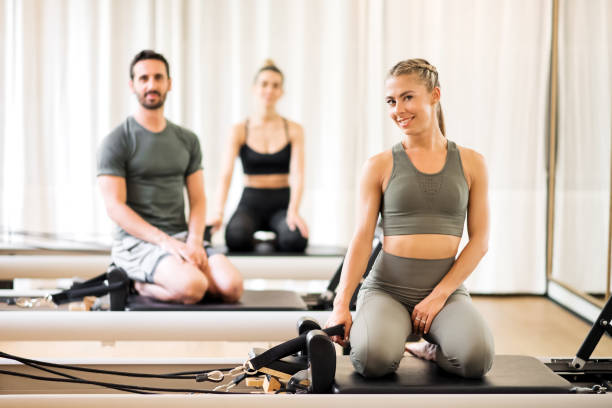 ジムで改革者のベッドでポーズをとる3人のアスリート - pilates machine 写真 ストックフォトと画像