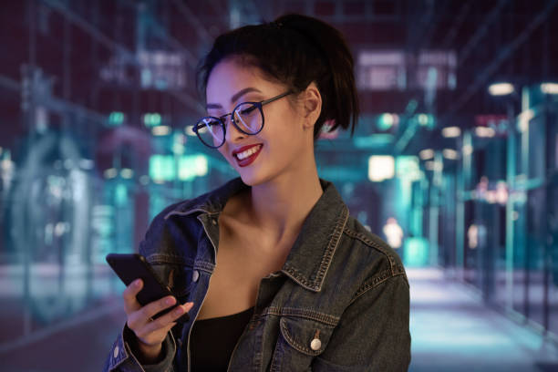 Woman Using a Smartphone in the City at Night stock photo
