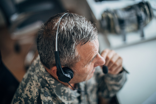 Army soldier wearing headphones and using computer