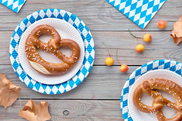 Beer Fest rustic background. Two prezels in blue and white checkered disposable paper plates. Flat lay on rustic wooden table decorated with Autumn decorations.