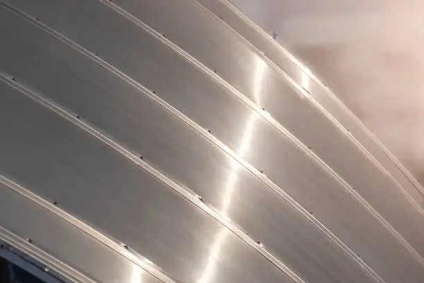 Shiny metal panels to cover shaped roof of modern building.