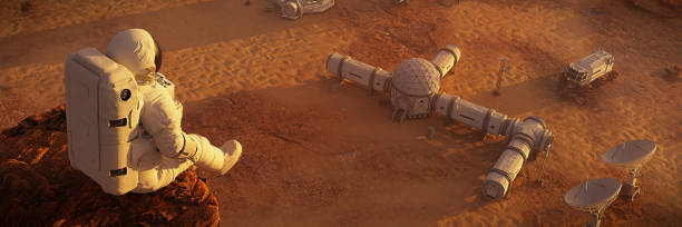 istock astronaut on planet Mars, sitting on a cliff above a research station  (3d space illustration banner) 1171285584