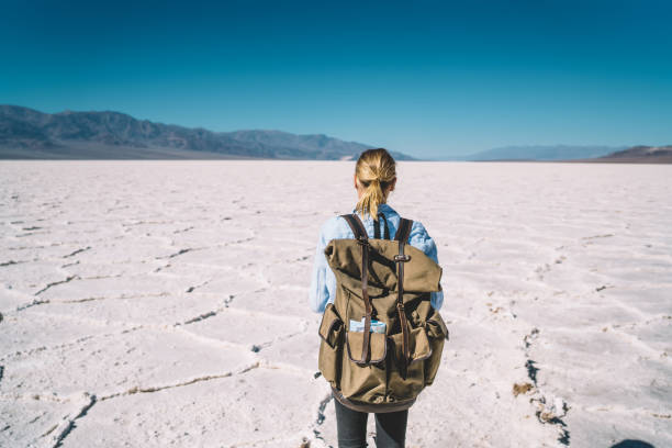 istock Back view of female traveler using smartphone camera for making selfie on scenic background of Death Valley,woman carrying backpack having journey in Badwater national park taking picture on mobile 1171291299