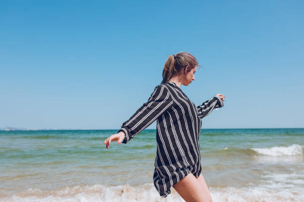 Young, gorgeous girl dancing on the beach of Albena, Bulgaria. With clear sky and sea as background.