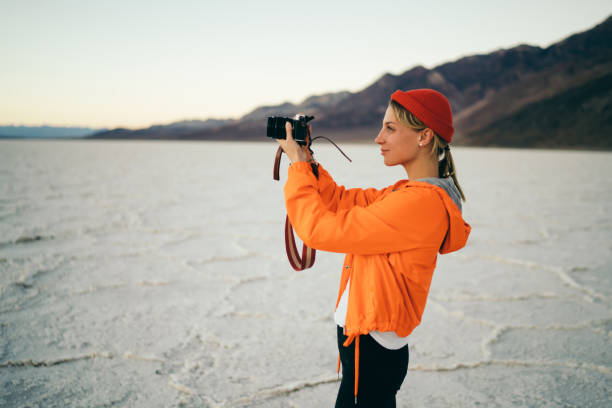 istock Attractive female photographer working during expedition to desolate environment in Badwater basin,young woman taking picture of dry lake landscape on professional camera having journey in california 1171297384