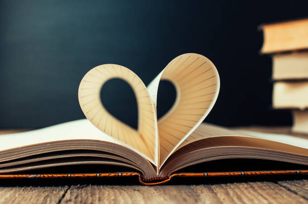 istock Sheets of a notebook in a cage wrapped in the shape of a heart.In the background is a stack of books and a black board.Education concept.Valentine's Day.Copy space.Rustic and vintage.Concept love. 1171298232