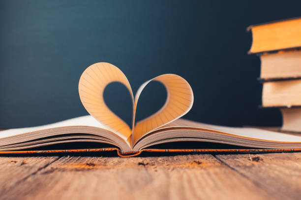 istock Sheets of a notebook in a cage wrapped in the shape of a heart.In the background is a stack of books and a black board.Education concept.Valentine's Day.Copy space.Rustic and vintage.Concept love. 1171301355