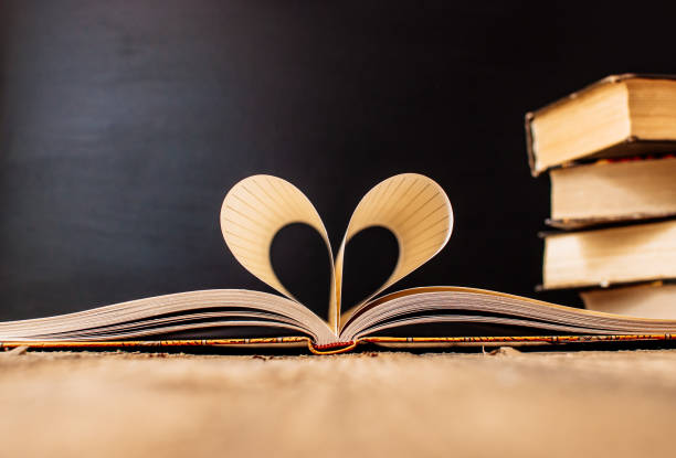 istock Sheets of a notebook in a cage wrapped in the shape of a heart.In the background is a stack of books and a black board.Education concept.Valentine's Day.Copy space.Rustic and vintage.Concept love. 1171301415