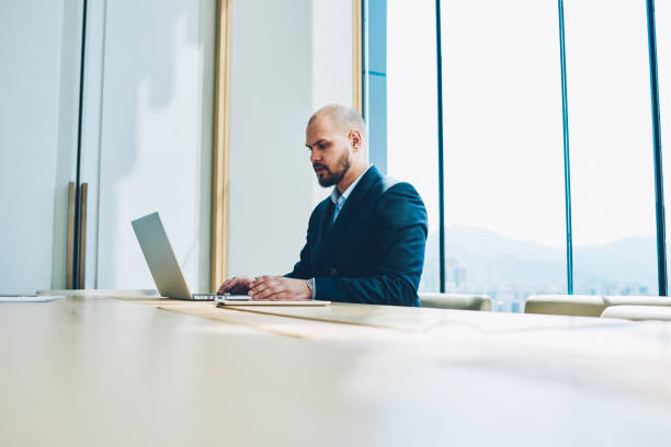 istock Bearded executive manager in formal apparel working on creating business presentation about financial accounting on computer device connected to wireless innternet sitting in modern office interior 1171301479