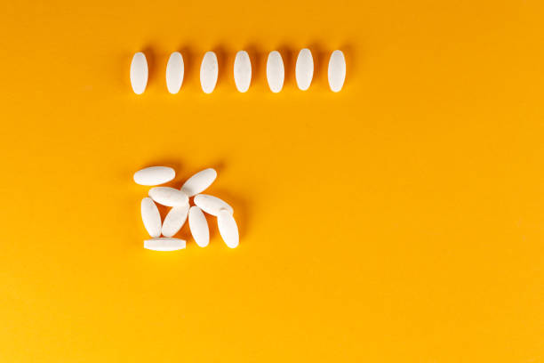 istock A scattering of white oval-shaped tablets on an orange background. 1171301748
