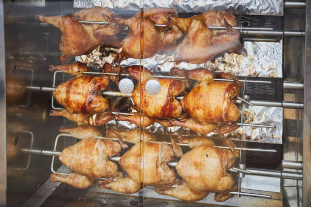 A few whole chickens are fried on an electric skewer A few whole chickens are fried on an electric skewer smoking meat rotisserie barbecue grill stock pictures, royalty-free photos & images