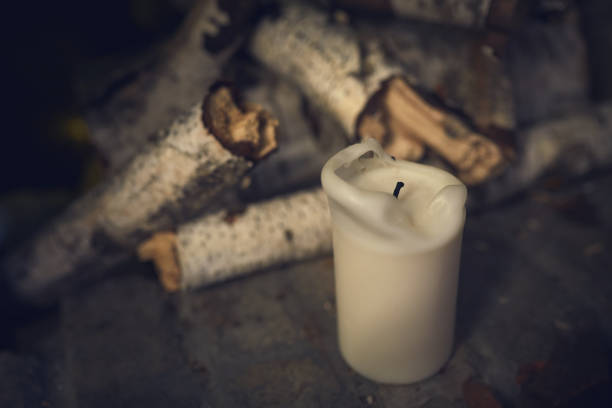 White extinct paraffin candle against a background of birch firewood