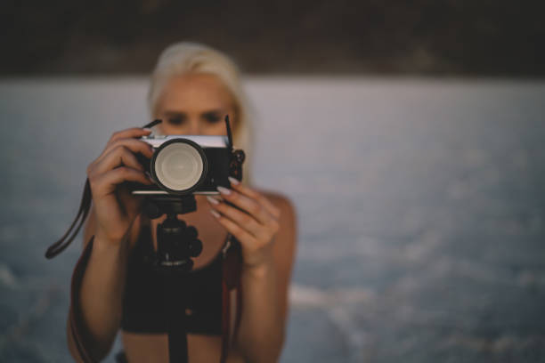 Selective focus on digital camera with modern objective for taking picture of wild environment on Death valley in evening , female tourist photographer shooting sunset in Badwater basin with dry lake