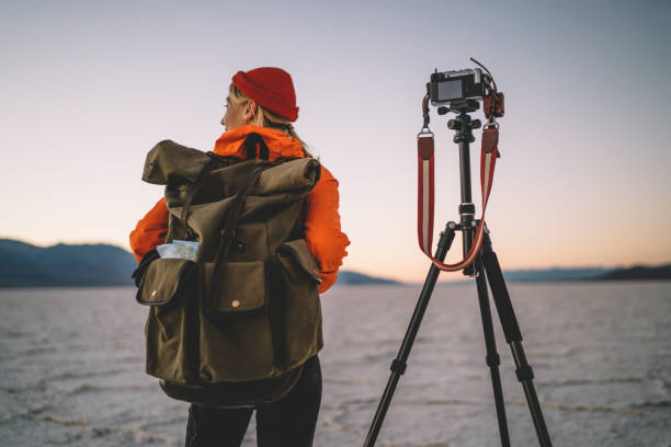 istock Back view of female photographer with backpack making preparation before starting to shoot video of scenic environment, woman taking photos of Badwater basin using modern equipment and tripod 1171307438