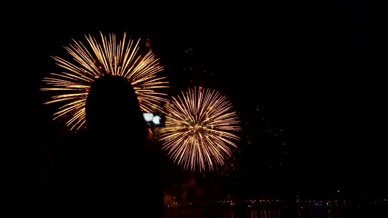 Silhouette of girl with smartphone on background of colorful fireworks.