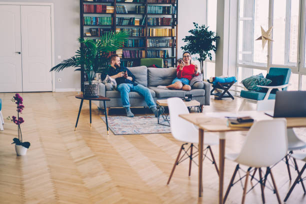 istock Cheerful couple sitting on comfortable couch in comfortable bright living room with contemporary furniture, happy young family spending time together in stylishly designed apartment using technology 1171314285