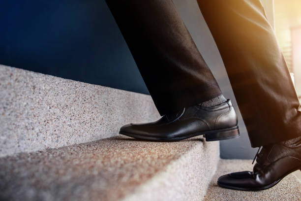 istock Motivation and challenging Career Concept. Steps Forward into a Success. Low Section of Businessman Walking Up on Staircase. Male in Black Formal Dress 1171318464