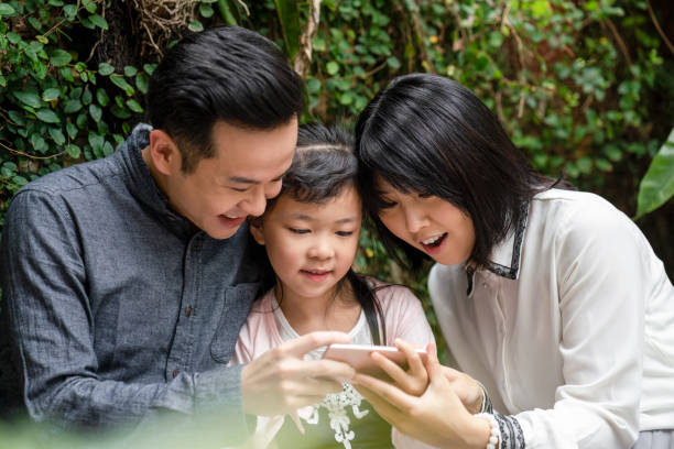 istock Happy parents showing mobile phone to daughter 1171321380