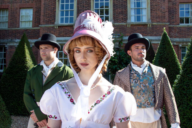 Handsome trio of men and a woman dressed in vintage clothing, standing in front of stately home Handsome male couple and beautiful woman dressed in vintage clothing standing outside of stately home. regency style stock pictures, royalty-free photos & images