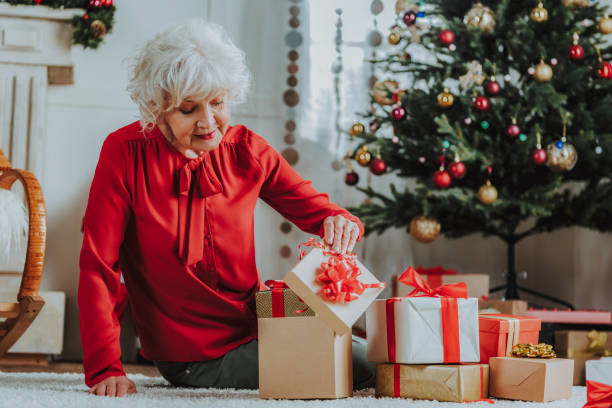 istock Happy old female is opening Christmas presents 1171326061