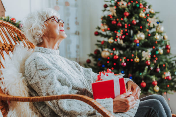 istock Senior lady is sitting with Christmas present 1171326108