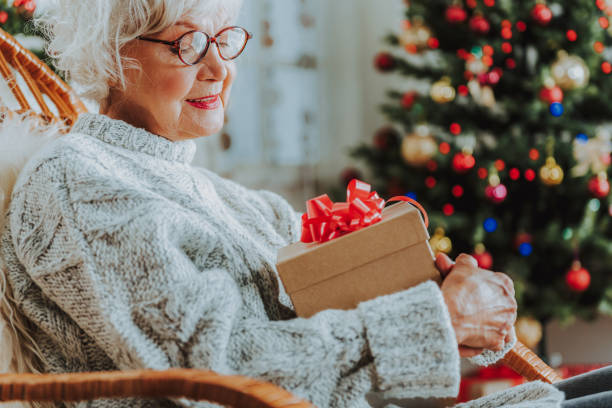 istock Smiling elderly woman sitting at home with gift 1171326118