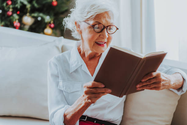istock Smiling old lady is reading book at home 1171326140