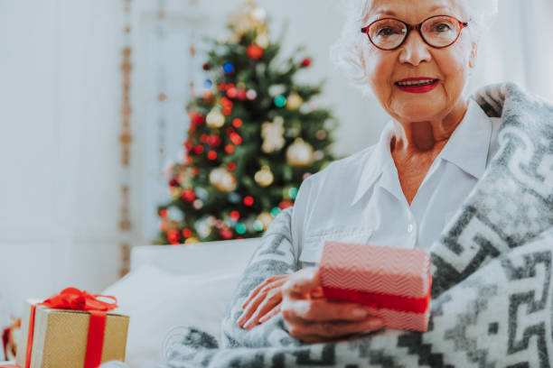 istock Smiling old female in glasses holding Christmas box 1171326199