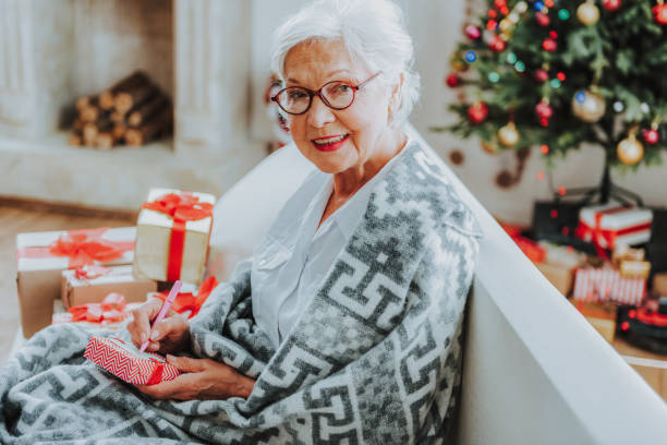 istock Cheerful senior lady in glasses is holding present 1171326226