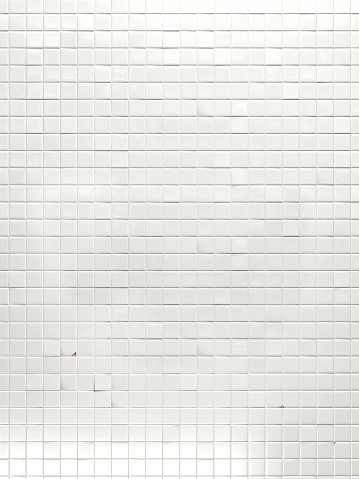 Wall of square, white, smooth tiles with cracks, imperfections, broken, chipped and crooked tiles. Realistic and illuminated in 3D.