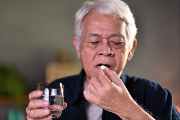 istock Asian senior man taking pills at home 1171336643