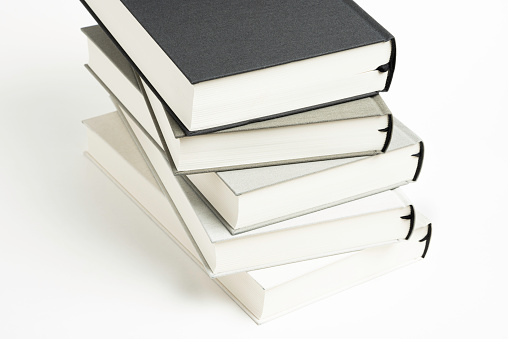 A disarrayed stack of five monochromatic cloth bound books set on a plain white background.