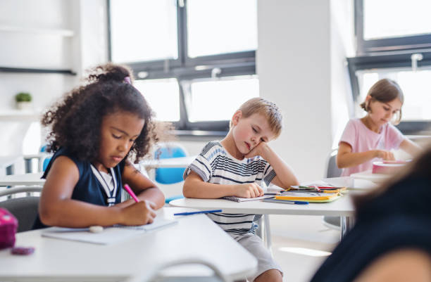 istock A small tired school boy sitting at the desk in classroom, sleeping. 1171340484