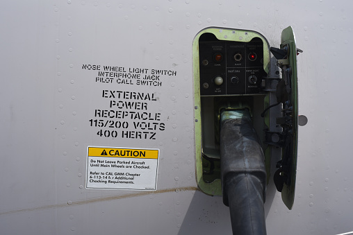 Close up of an external power cord plugged into an external power receptacle on a commercial aircraft.