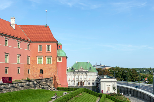 Warsaw, Poland - August, 2019 : Man resting on the bench in a front of Copper-Roof Palace and The Royal Castle in Warsaw, located in the Castle Square