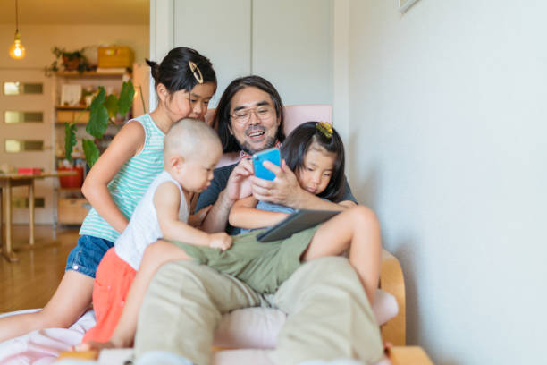 padre moderno cuidando de sus hijos en casa - japonés oriental fotos fotografías e imágenes de stock