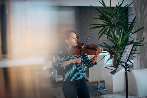 Young woman violinist practicing at home