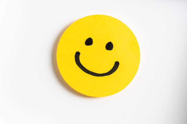dibujo de un emoticono sonriente feliz sobre un papel amarillo y fondo blanco. - insignia símbolo fotos fotografías e imágenes de stock