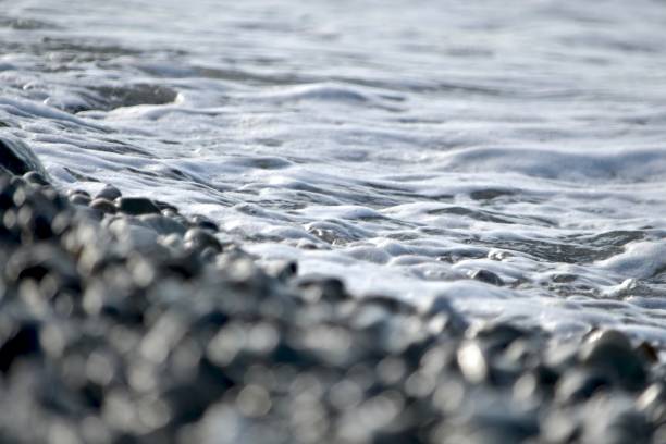 istock Pebble beach covered by sea foam. 1171350043