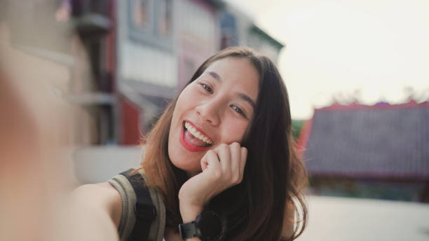istock Cheerful beautiful young Asian backpacker blogger woman using smartphone taking selfie while traveling at Chinatown in Beijing, China. Lifestyle backpack tourist travel holiday concept. Point of view. 1171351510