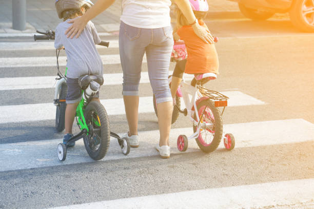 madre con hijo e hija con una bicicleta en una cebra - familia de cruzar la calle fotografías e imágenes de stock
