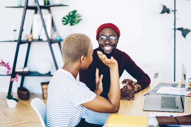 istock Cheerful african american hipster guy laughing during friendly conversation with female colleague , positive dark skinned couple having fun while discussing plans for vacation sitting at desktop 1171354226