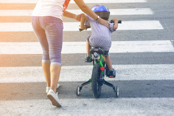 mother with son with a bike on a zebra - child bicycle cycling danger imagens e fotografias de stock