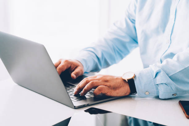 istock Closeup view of corporate entrepreneur working on laptop computer at table in bright interior. Male hands keyboarding text message on modern netbook.Businessman shopping online on market website on pc 1171354465
