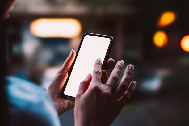 istock Woman's hands holding mobile phone with big copy space touch screen outdoors with evening bokeh light of city on background. Close up view of female person using smartphone app for online shopping 1171354487