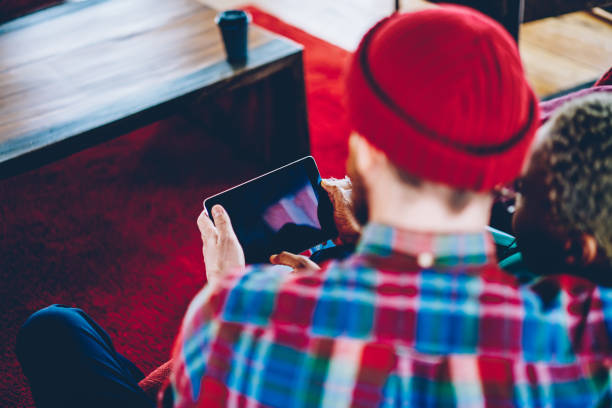 istock Cropped back view of couple in love updating software and installing application on modern touch pad using wireless 4G internet.Young marriage watching movie on website on digital tablet device 1171358239