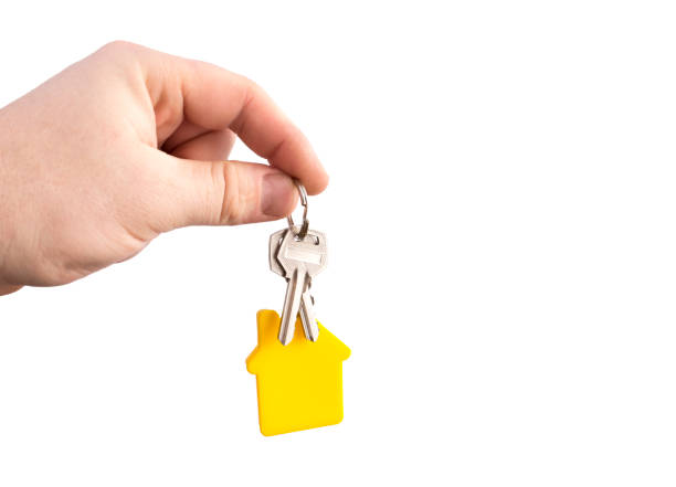 istock key with a yellow shaped house on a chain in a hand on a white background. 1171364017